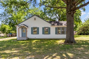 A single-story house with a gabled roof, a front porch, and a large tree in front. - Sweet Cherry Escape | JZ Vacation Rentals (Warrenton)