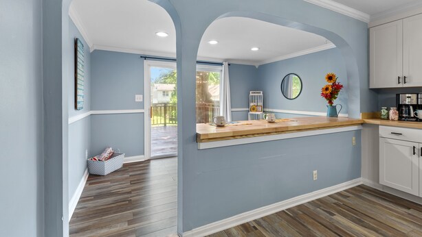 A kitchen with light blue walls, wooden flooring, and white cabinets. - Sweet Cherry Escape | JZ Vacation Rentals (Warrenton)