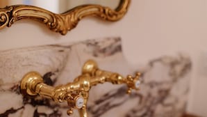 Ein Badezimmer mit einem Marmorwaschbecken und einem verzierten goldenen Wasserhahn.