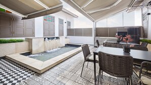 Una veranda coperta all'aperto con piscina, zona salotto e televisore a schermo piatto.