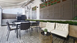 Un'area pranzo esterna moderna con tavolo e sedie, un divano e un cesto decorativo.