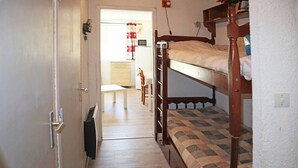 A narrow hallway with a wooden door, a bench, and a bunk bed with a patterned mattress. - Lovely 4-person studio with ski in ski out (LES ORRES 1650)