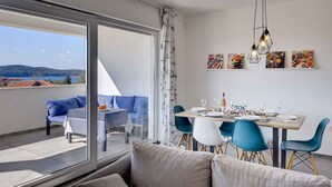 Ein moderner Essbereich mit einem Tisch für vier Personen, blauen Stühlen und Blick ins Freie.