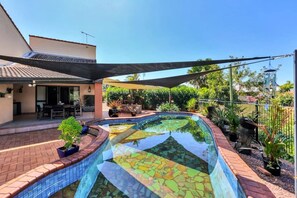 A swimming pool with a mosaic tile design, surrounded by a brick patio and potted plants. - Tranquil Townhouse: HUGE Pool & Golf Course views (Marrara)