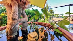 Une statue de pierre dans un bassin, avec un parapluie jaune en arrière-plan.