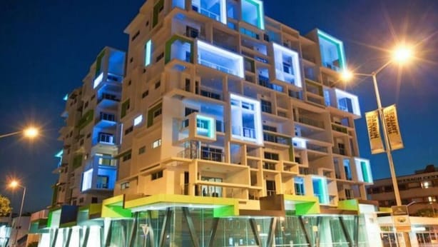 A multi-story hotel with a modern architectural design, featuring balconies and a glass facade.