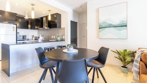 A modern kitchen with a central island, dining chairs, and a table.