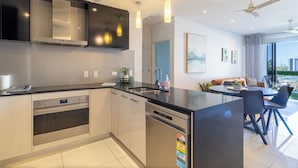 A modern kitchen with built-in appliances, a dining area with a table and chairs, and a ceiling fan.