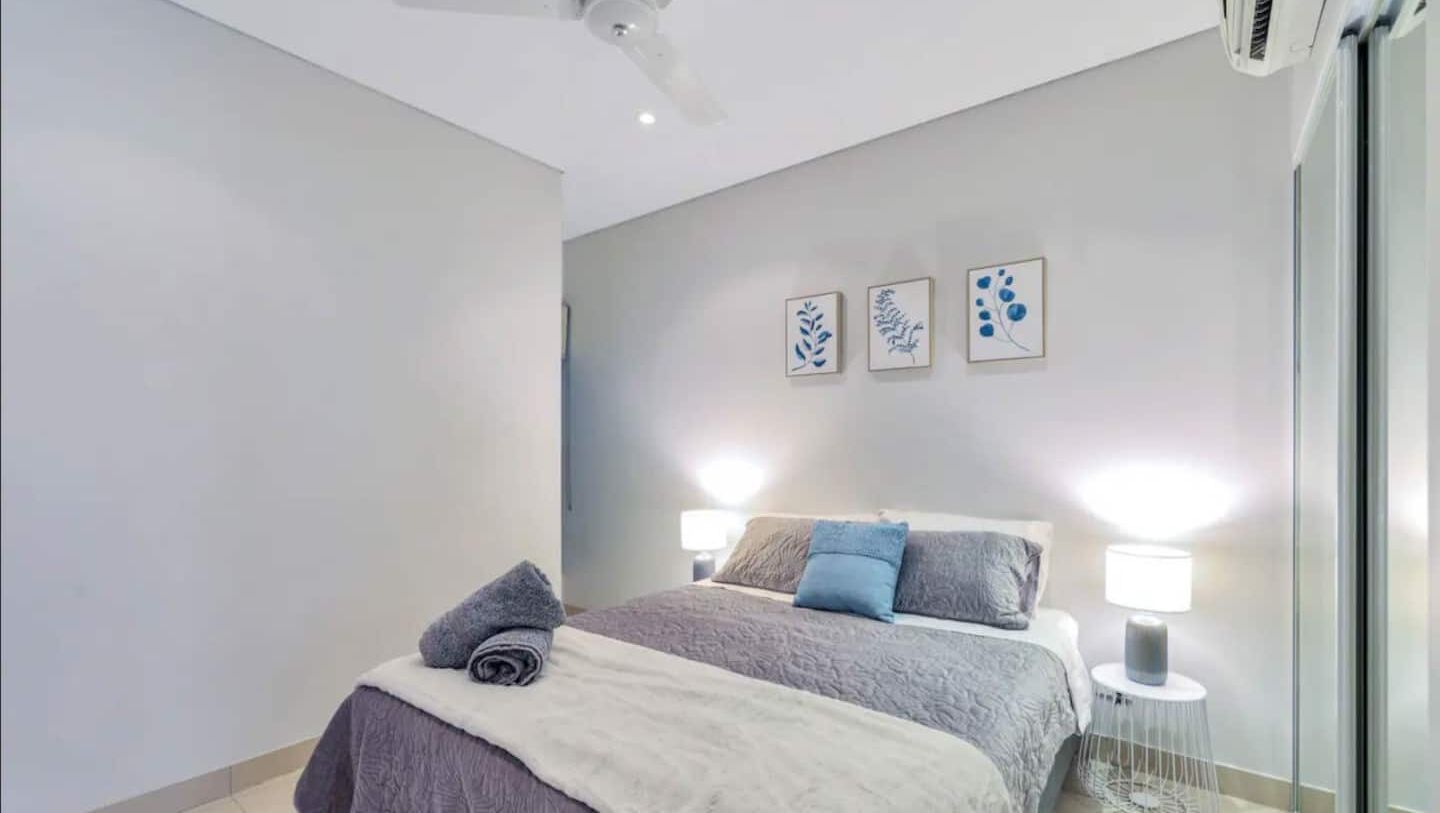 A bedroom with a bed, two bedside lamps, and three wall-mounted pictures.