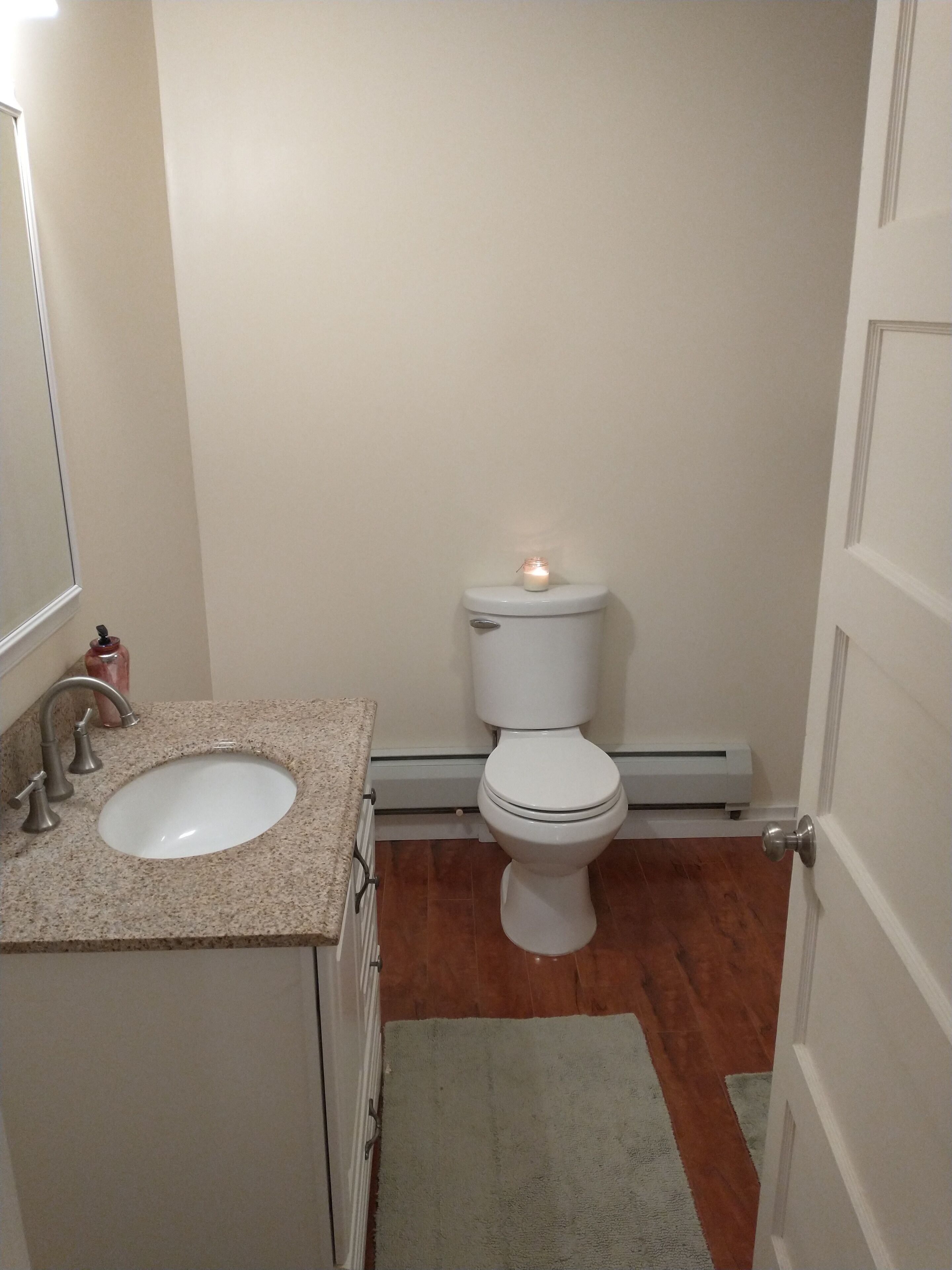 A small bathroom with a white toilet, a sink, and a towel on the floor.
