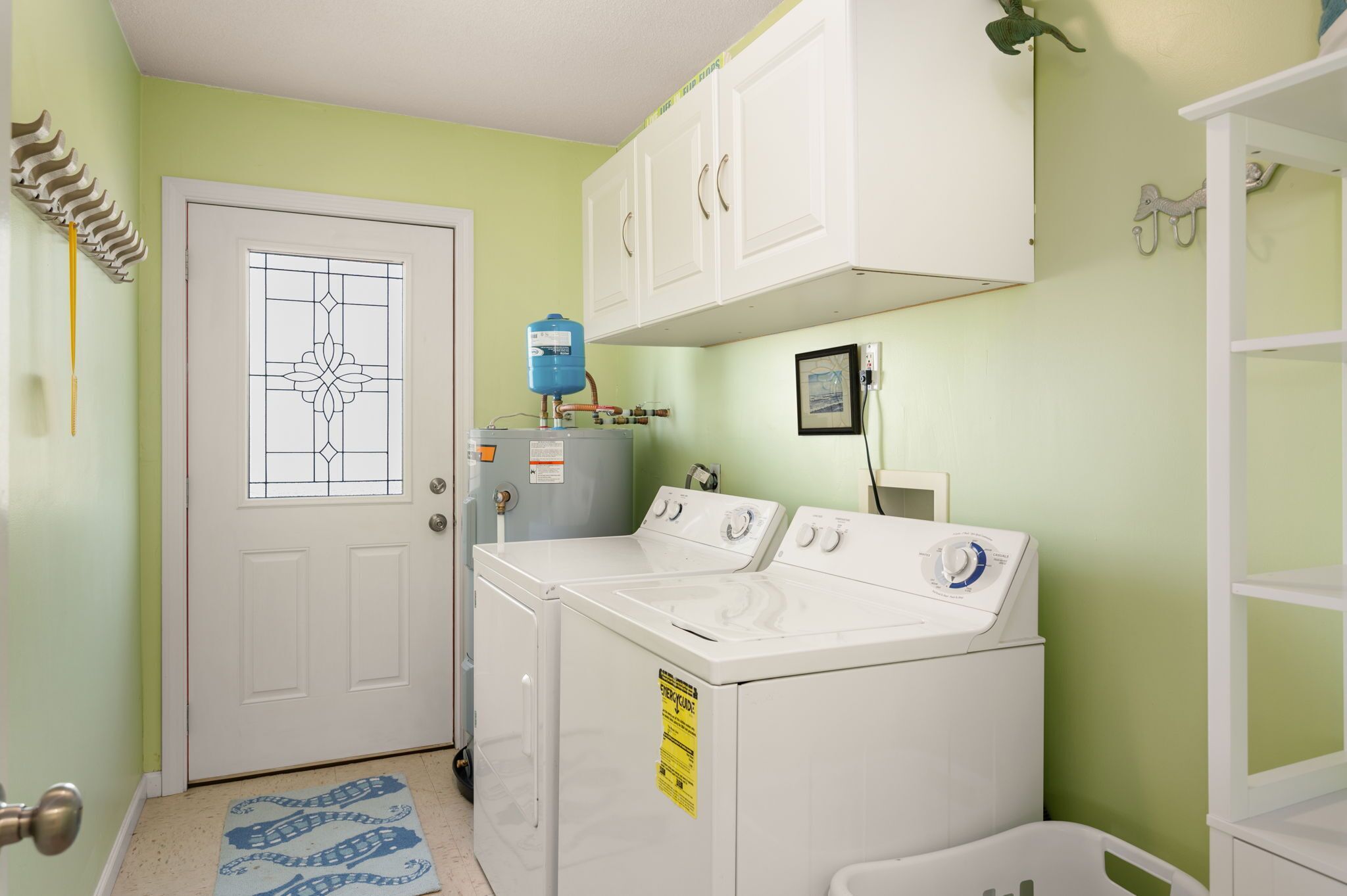 A laundry room with a white door, a water heater, and a washing machine.