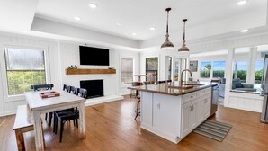 A spacious kitchen with white cabinetry, a large island, and a dining area with a bench. - "SALT WIND" HAS GULF VIEWS, STEPS TO BEACH, SECLUDED & PEACEFUL! (Mexico Beach)