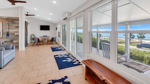 A spacious living area with large windows, a ceiling fan, and a view of the ocean. - "SALT WIND" HAS GULF VIEWS, STEPS TO BEACH, SECLUDED & PEACEFUL! (Mexico Beach)