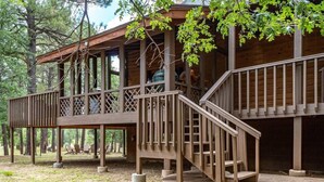 Une cabane en bois dotée d’une terrasse couverte et d’un escalier menant à un deuxième étage.