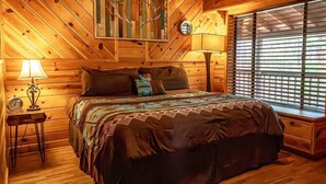 Une chambre confortable dans un chalet en bois, avec un lit, une table de chevet, une lampe et une fenêtre avec des stores.