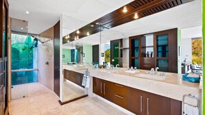 A modern bathroom with a large mirror, dual sinks, and wooden cabinets. - Suite 2 - Casa Samo Conchas Chinas (Puerto Vallarta)