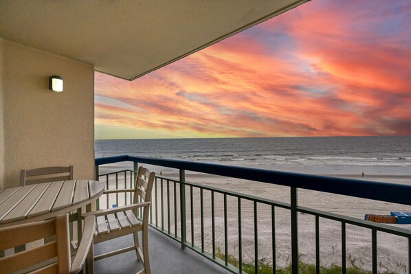 A balcony with a view of the ocean and a sunset.