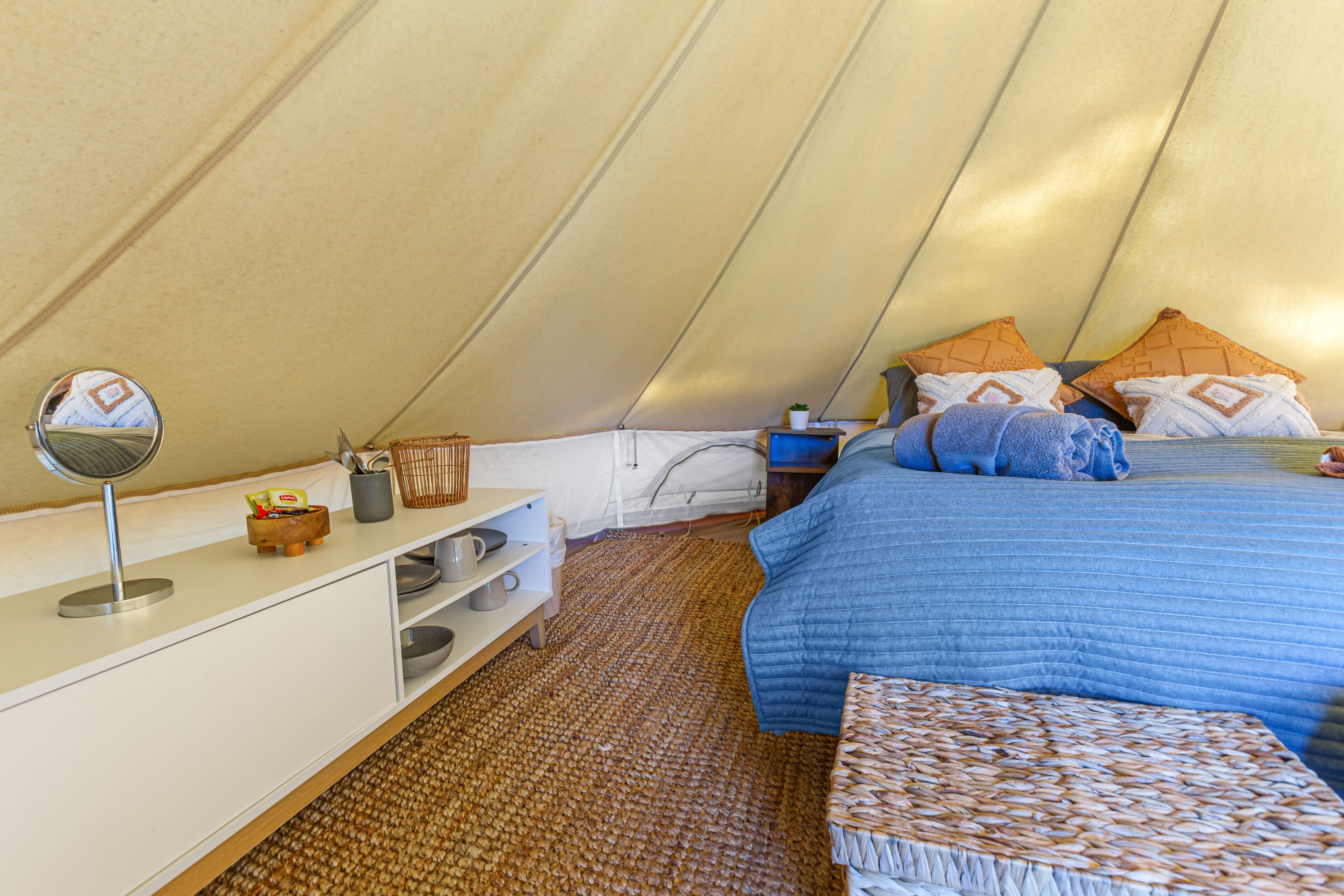 Alojamento em tenda com cama, mesa de cabeceira e um pequeno espaço de estar.