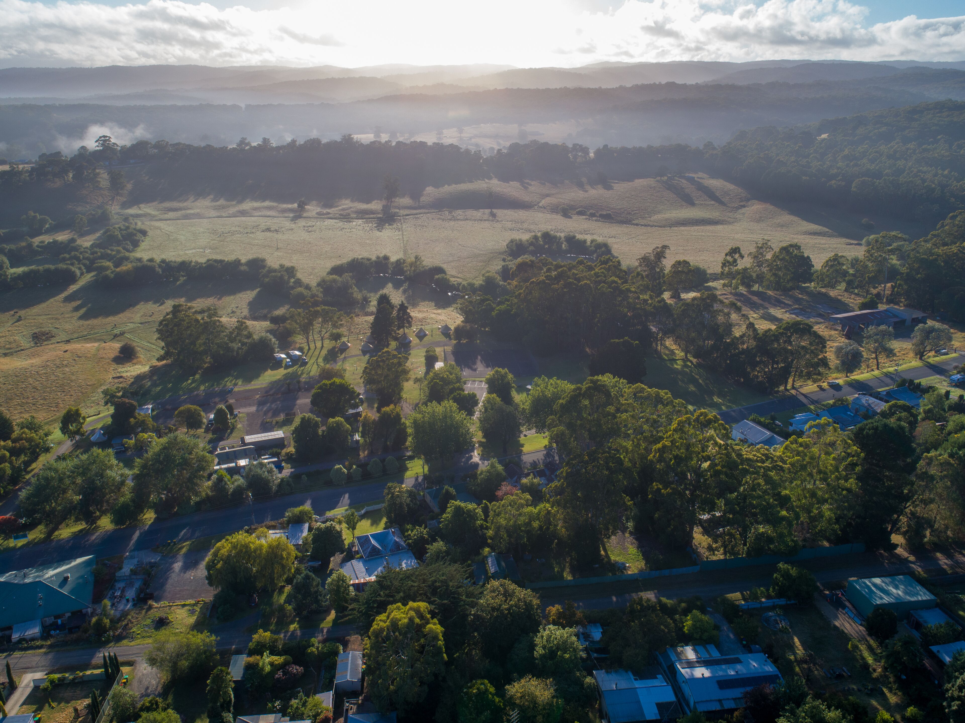 An aerial view of a residential area with houses, roads, and green fields.