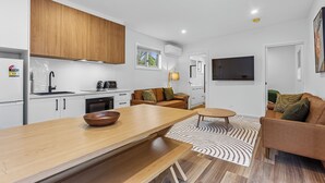 Een moderne keuken met witte kastjes, een houten aanrechtblad en een zithoek met een bank en tafel.