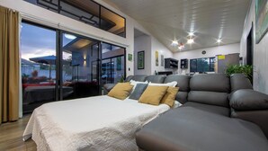 Een moderne slaapkamer met een groot bed, een slaapbank en een balkon met uitzicht.