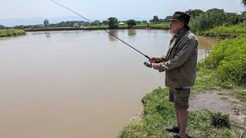 Guests can fish from the river's tranquil waters, surrounded by lush greenery and distant hills.