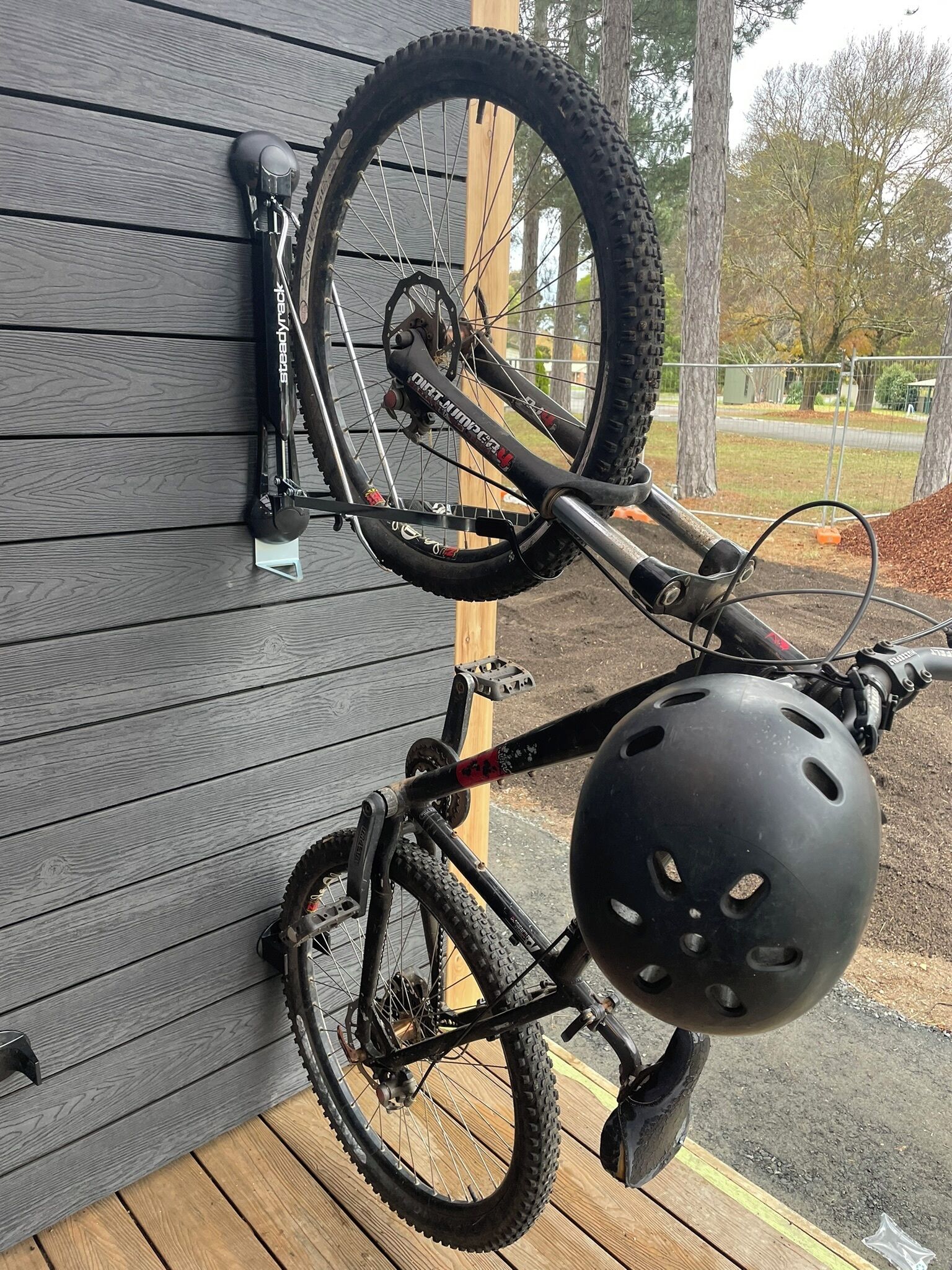 A bicycle mounted on a wall, with a helmet hanging below it.