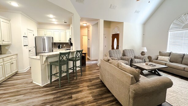 A spacious living area with a kitchen, a ceiling fan, and a large window.