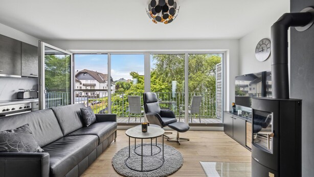 Un salon moderne avec un canapé, des fauteuils, une table basse ronde et une cheminée.