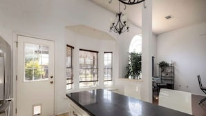 A kitchen with a black countertop, white cabinets, and a chandelier. - Villa with Pool, BBQ and More (Flower Mound)