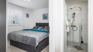 A bedroom with a bed, a window with curtains, and a shower area with glass doors. - Gorgeous apartment in Malinska with swimming pool (Malinska)