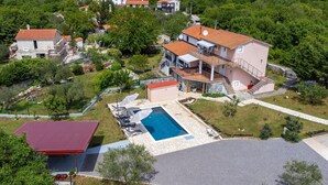 A residential property with a swimming pool, a covered patio, and a red-roofed building. - Gorgeous apartment in Malinska with swimming pool (Malinska)