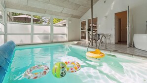 An indoor swimming pool with clear water, a blue towel, and colorful inflatable rings. - Beautiful home in Glesborg with sauna (Glesborg)