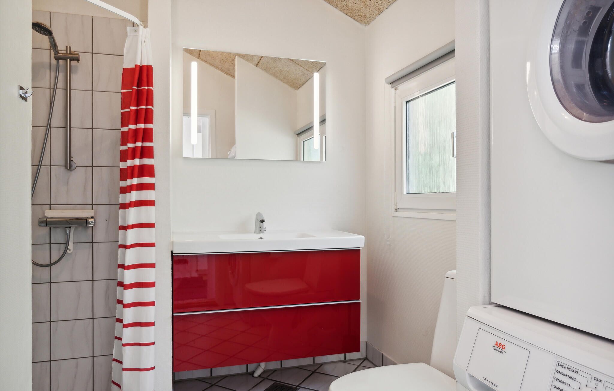 A bathroom with a shower, a sink, a mirror, and a toilet.