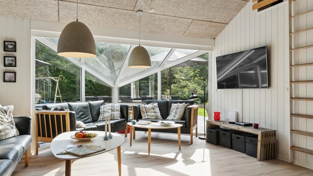 A modern living room with a sofa, coffee table, and TV. - Beautiful home in Glesborg with sauna (Glesborg)