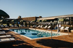 Una piscina al aire libre, sombrillas, sillones reclinables de piscina