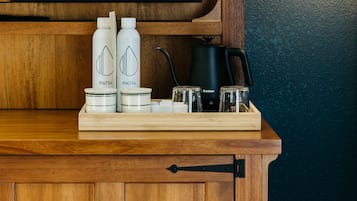 A wooden cabinet with a tray holding two bottles, a jar, and a kettle.
