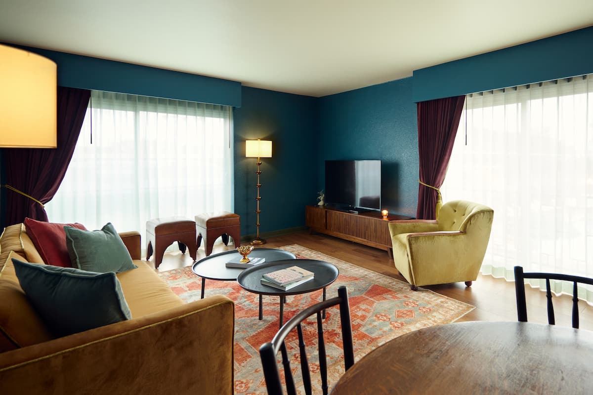 Een woonkamer met een bank, fauteuils, een salontafel, een televisie en een lamp.