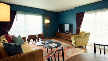 A living room with a sofa, armchairs, a coffee table, a TV, and a lamp.