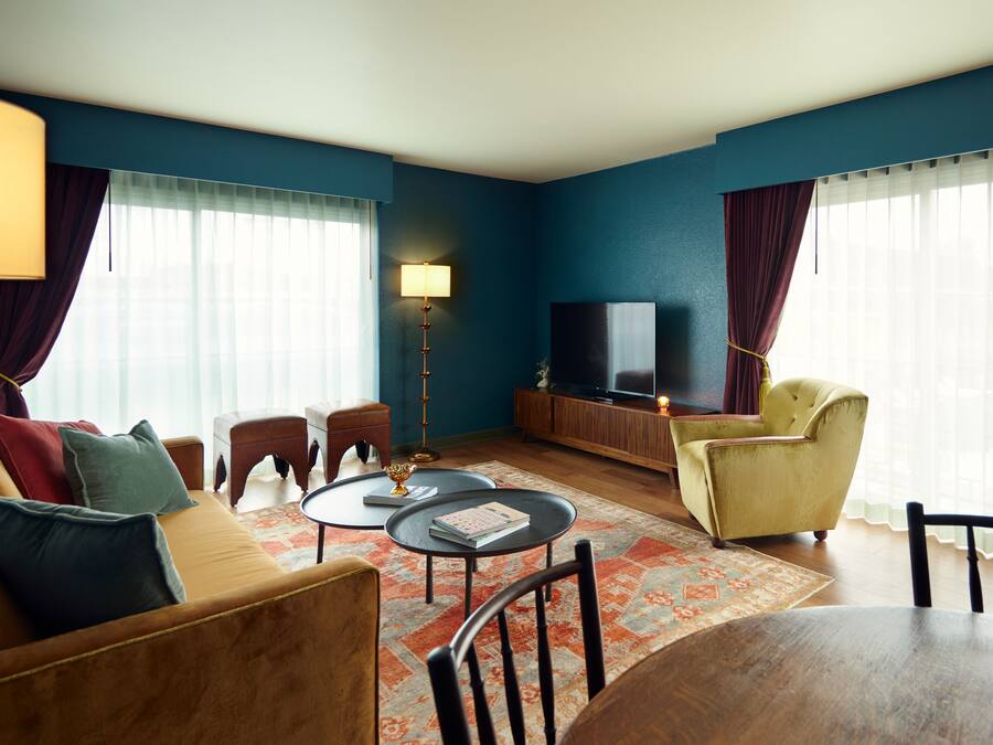 A living room with a sofa, armchairs, a coffee table, a TV, and a lamp.