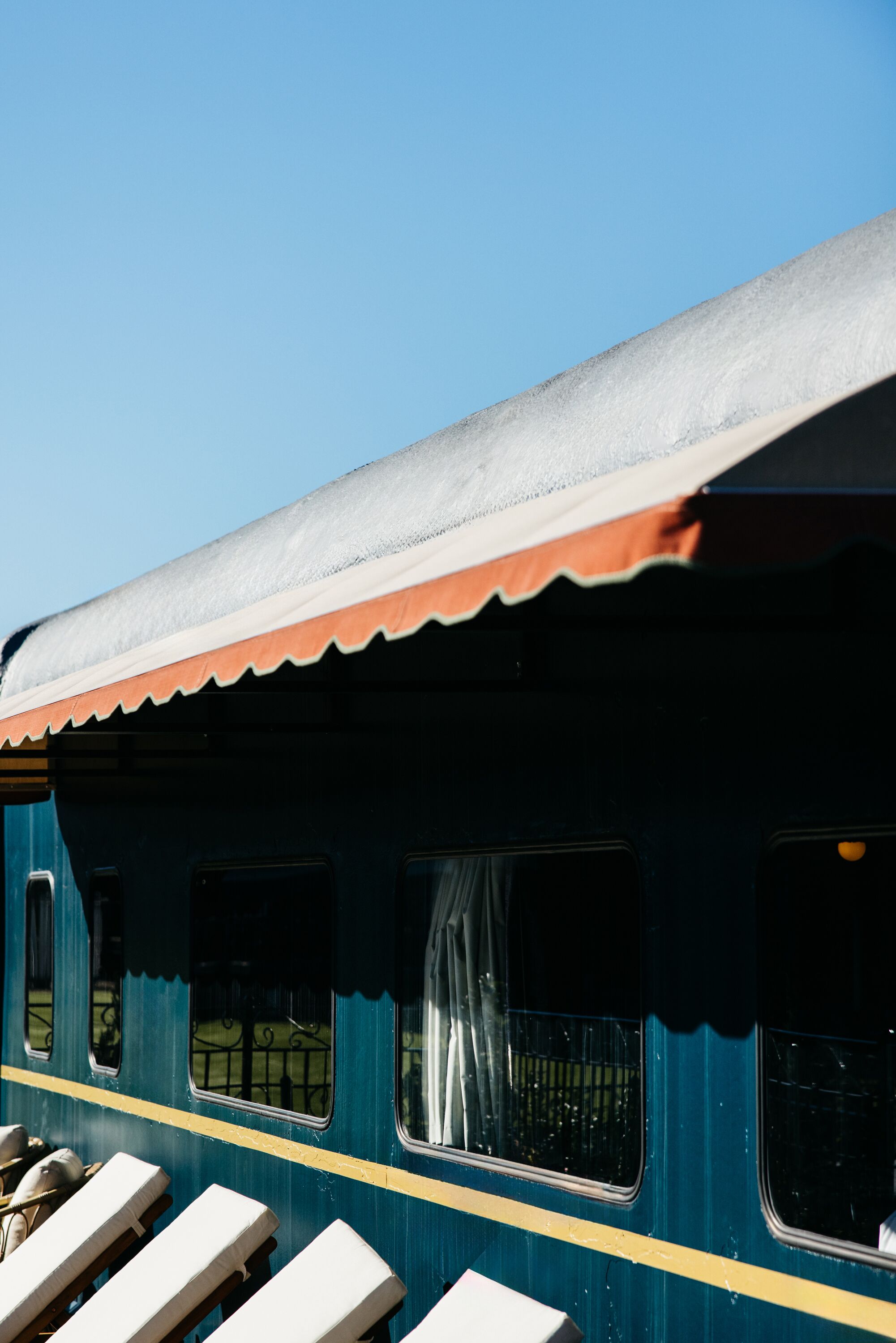 A train with blue and yellow exterior, white windows, and a red roof.