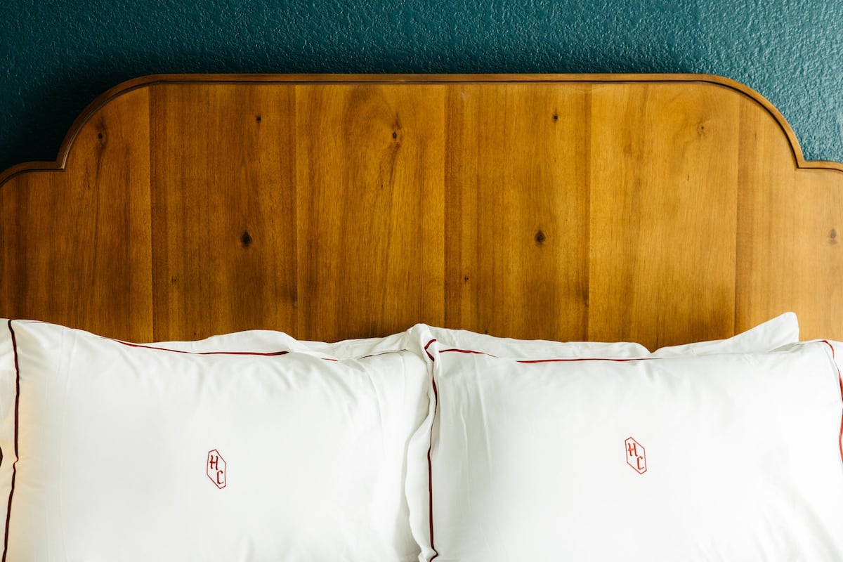 Een houten hoofdbord met twee witte kussens met een rood logo.