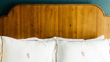 A wooden headboard with two white pillows featuring a red logo.