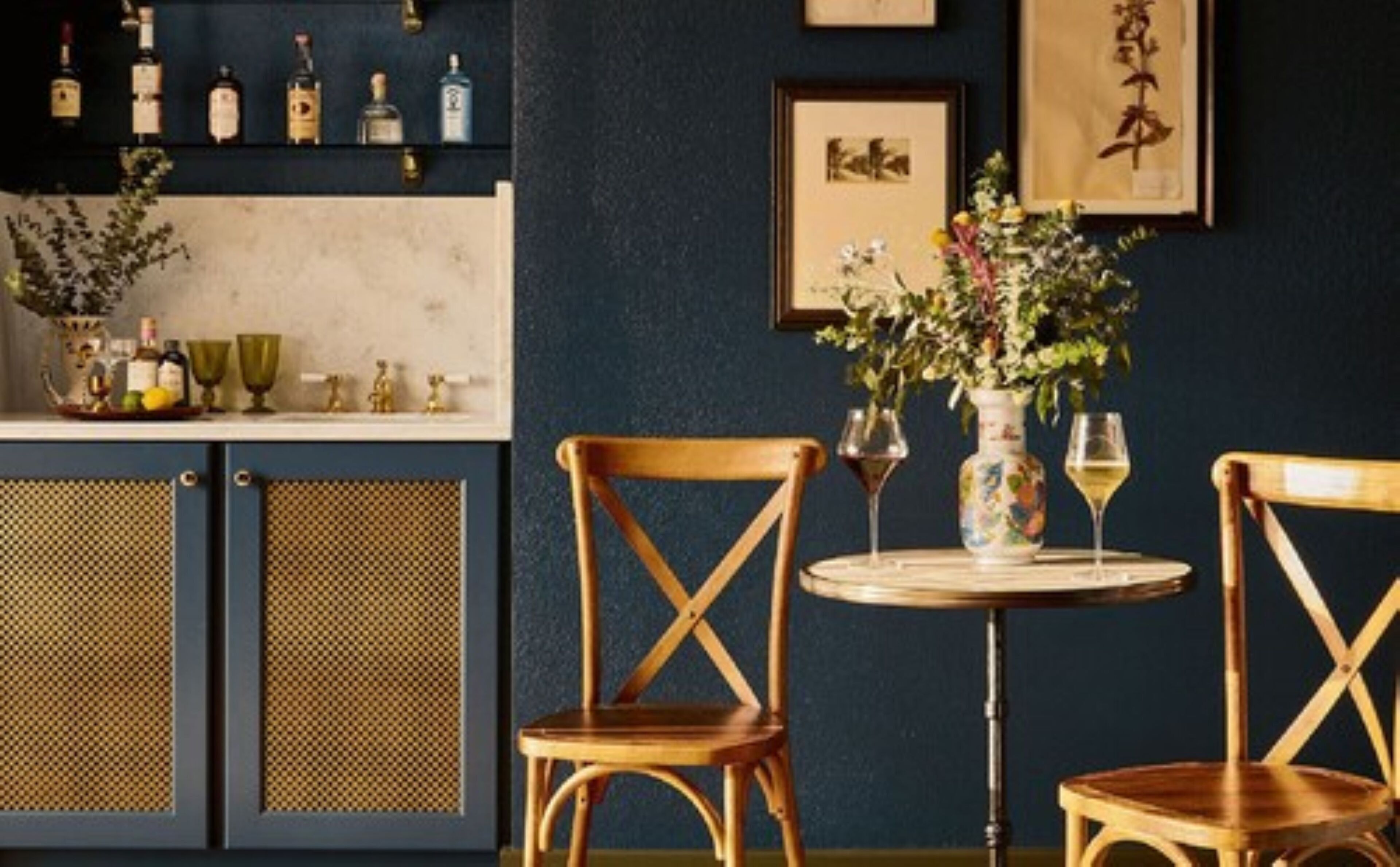 A bar area with wooden chairs, a round table, and a vase with flowers.