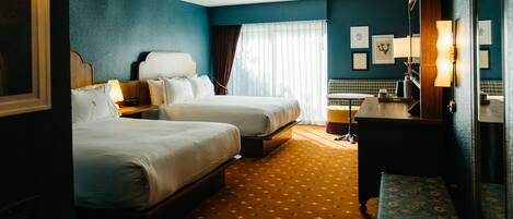 A hotel room with two beds, a desk, a chair, and a bathroom.