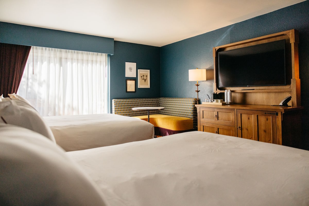 Een hotelkamer met twee bedden, een televisie, een klein tafeltje en een lamp.