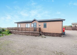 A wooden building with a gravel driveway and a wooden fence. - Sea View Lodge 3 Pet Friendly (Kirkcudbright)