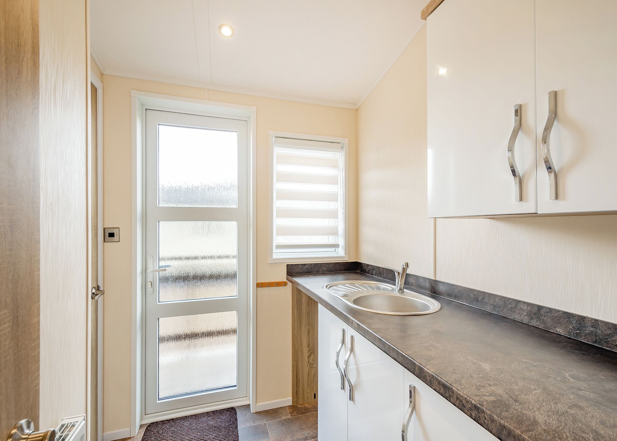 A kitchen with a sink, cabinets, and a door with frosted glass panels.