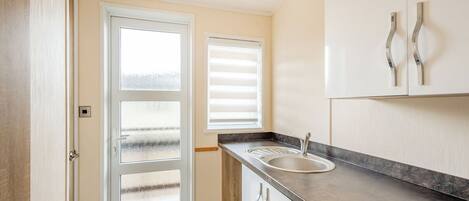 A kitchen with a sink, cabinets, and a door with frosted glass panels.