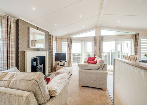 A spacious living room with a fireplace, a television, and a balcony with curtains.